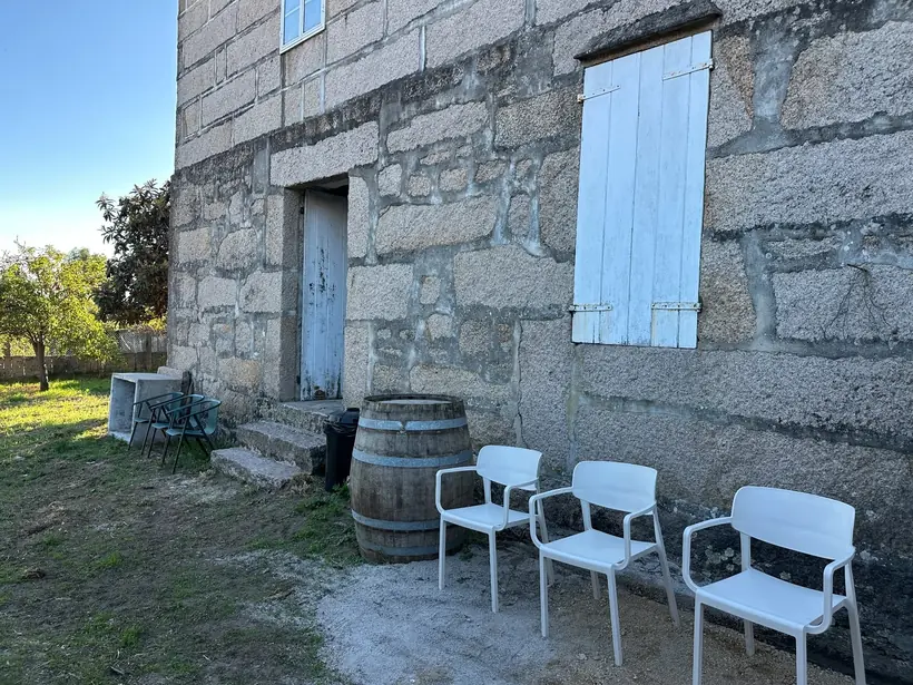 Parede de pedra con portas claras, cadeiras e un barril