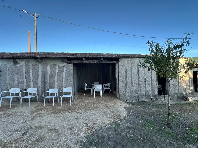 Alpendre de pedra con mesas e cadeiras brancas